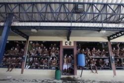 Imprisoned gang members, wearing protective face masks, look out from behind bars during a media tour of the prison in Quezaltepeque, El Salvador, Sept. 4, 2020.