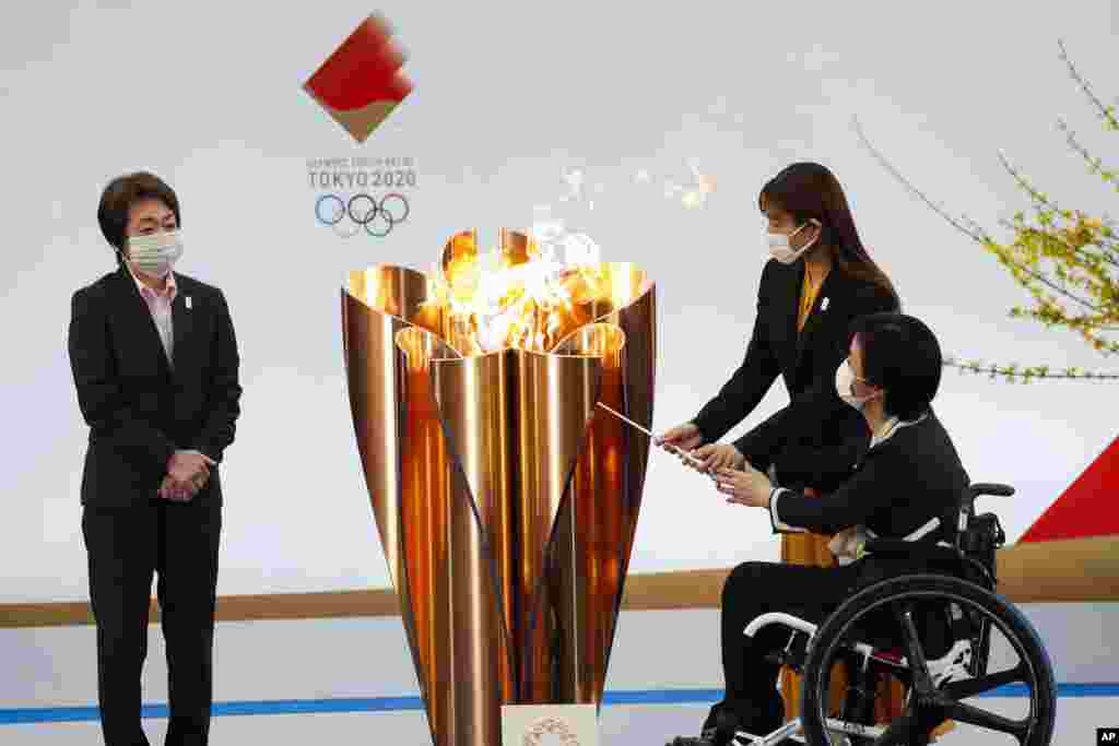 Tokyo 2020 President Seiko Hashimoto, left, watches Japanese actress Satomi Ishihara and Paralympian Aki Taguchi light the celebration cauldron on the first day of the Tokyo 2020 Olympic torch relay in Naraha, Fukushima prefecture, northeastern Japan.