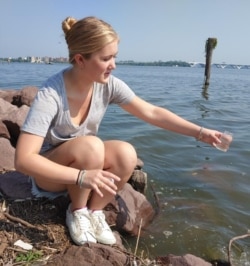 Emma Carter, a volunteer, takes water samples from the Potomac River in Alexandria, Virginia. (Deborah Block/VOA)
