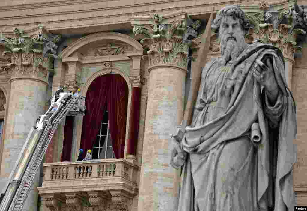 Pekerja memasang tirai merah di balkon Basilika Santo Petrus di Vatikan. Para kardinal gereja Katolik Roma memulai konklaf hari Selasa besok untuk memilih Paus ke-266. Setelah terpilih dalam konklaf, Paus yang baru akan muncul di balkon ini.