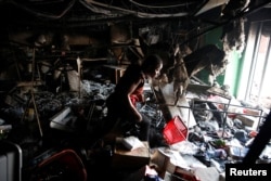 Una mujer entra a un supermercado que fue saqueado durante las protestas contra los aumentos de los precios del combustible en Puerto Príncipe, Haití, el 8 de julio de 2018. REUTERS / Andres Martinez Casares