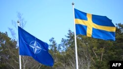 Zastava NATO-a podignuta je pored zastave Švedske (R) na ceremoniji u bazi mornarice Musko u Stokholmu marta 2024. godine, povodom ulaska Švedske u alijansu.