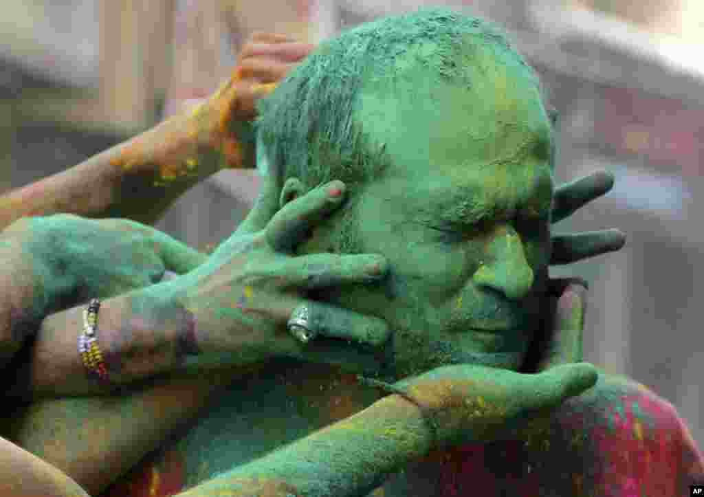 Indians smear colored powder on each other as they celebrate Holi in Jammu.