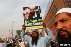 FILE - A supporter of Islamic charity organization Jamaat-ud-Dawa (JuD) carries a sign during a protest in Karachi, Pakistan, Feb. 3, 2017.