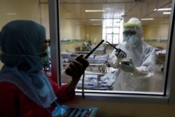 Nakes berbicara melalui walkie-talkie di ruang isolasi untuk pasien virus corona (Covid-19) di Rumah Sakit Persahabatan, Jakarta, 13 Mei 2020. (Foto: Reuters)
