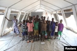 FILE - Children who fled fighting in South Sudan pose for a photograph inside a tented classroom at Bidi Bidi refugee’s resettlement camp near the border with South Sudan, in northern Uganda Dec. 7, 2016.