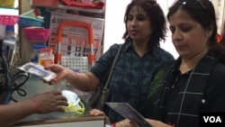 Poonam Sharma, right, looks at masks which many city residents have been purchasing in recent days. (A. Pasricha/VOA)