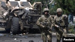 FILE - NATO soldiers walk at the site of a suicide bomb attack in Kabul, Afghanistan, June 30, 2015.