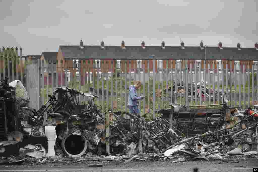 A man walks past a burnt out bus on the Shankill road in West Belfast, Northern Ireland. Authorities sought to restore calm after Protestant and Catholic youths in Belfast hurled bricks, fireworks and gasoline bombs at police and each other. 