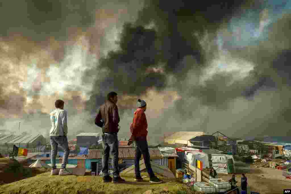 Beberapa migran di Calais, Perancis utara menonton dibongkarnya kamp pengungsi "Jungle" di mana 6.000-8.000 migran tinggal dalam kondisi yang memprihatinkan.