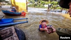 A boy gets food donation from a volunteer at a flooded area in Quang Binh province, Vietnam, Oct. 22, 2020.