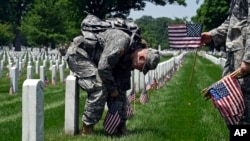 សមាជិកនៃ Old Guard លោក Pvt. Brandon Hyer (ឆ្វេង) មកពីក្រុង Kansas និងលោក Pvt. Brad Dixon នៃក្រុង Baltimore, Md., បានដាក់ទង់ជាតិខាងមុខផ្លាកផ្នរនៅឯទីបញ្ចុះសពជាតិ Arlington កាលពីថ្ងៃទី២៦ ឧសភា ២០១៦។ 