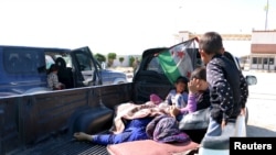 Civiles, heridos por lo que activistas dicen fue un ataque del groupo Estado islámico en Kobani, esperan con sus familiares para cruzar la frontera hacia Turquía.
