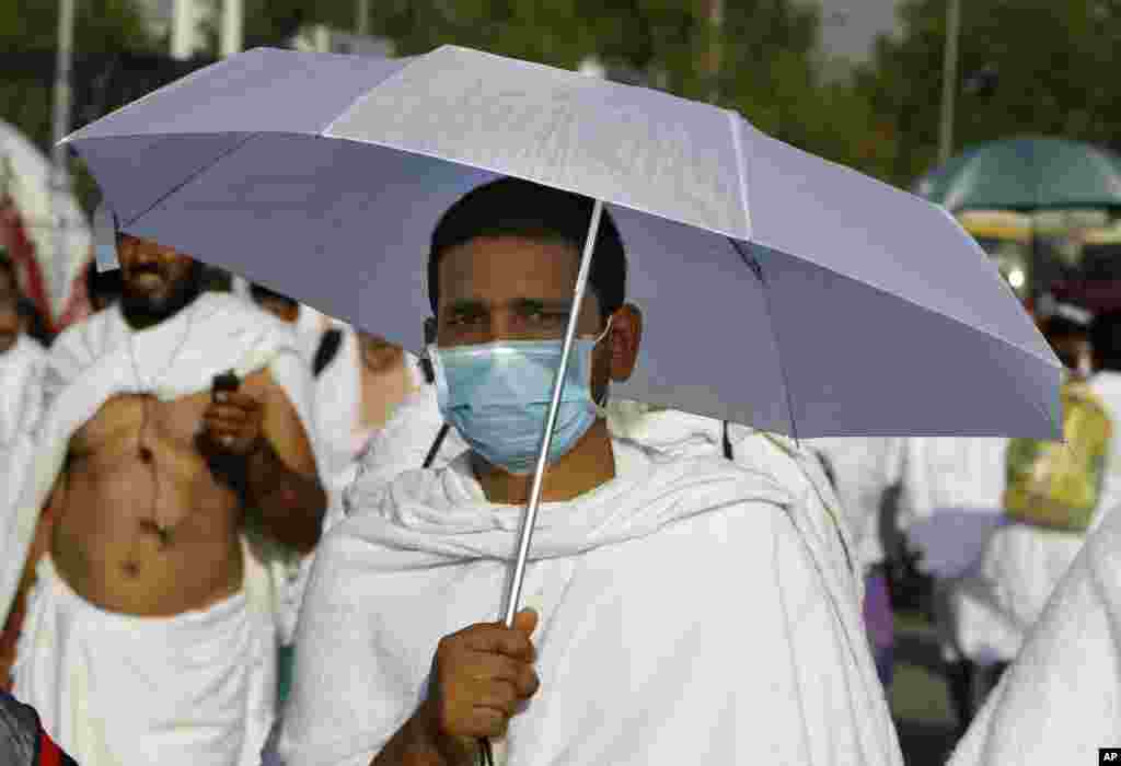 Seorang jamaah memakai masker saat berjalan di Padang Arafah, dekat Mekkah, Arab Saudi.