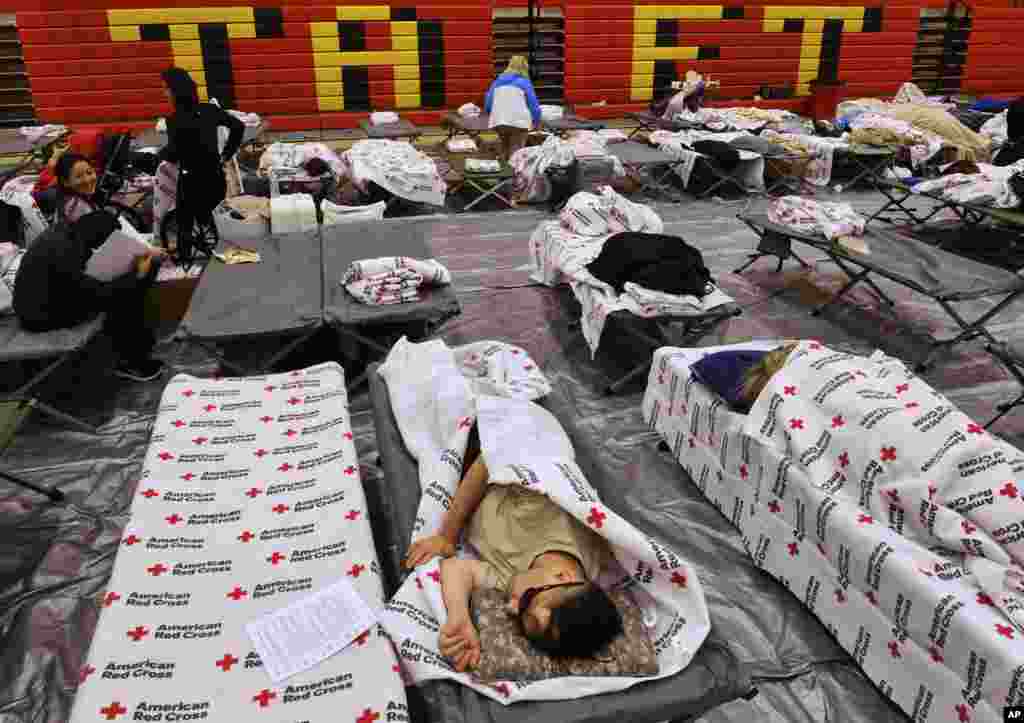 Evacuees from a wildfire rest on cots and blankets supplied by the Red Cross in the gymnasium at Taft Charter High School in the Woodland Hills section of Los Angeles, Nov. 9, 2018.