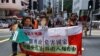 Pro-democracy demonstrators hold up a banner and portraits of jailed Chinese civil rights activists, lawyers and legal activists as they march to the Chinese liaison office in Hong Kong, June 25, 2020. 
