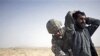 A US Army soldier searches an associate of a suspected Taliban IED placer, seen in a wheelbarrow, who was killed in a coalition missile strike in Zhari district, Kandahar province (File)