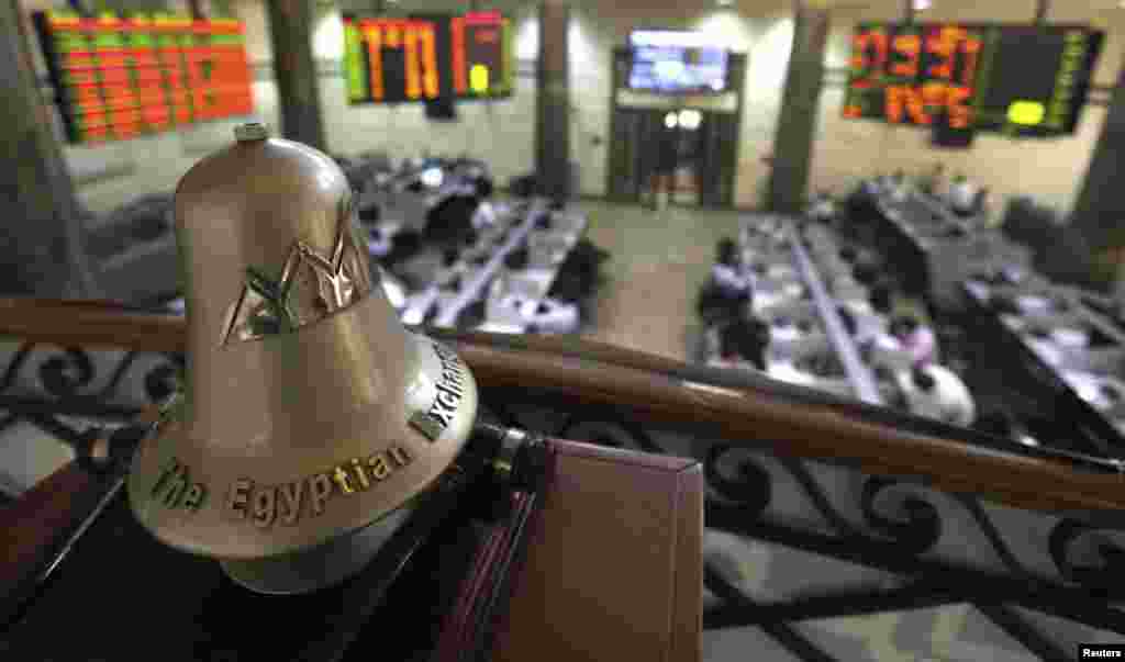 Para pialang saham bekerja di bawah lonceng Bursa Efek Mesir di Kairo. Bursa saham Mesir mencatat rekor terendah dalam 4 bulan terakhir pada hari Minggu, sebagai akibat dari memburuknya ekonomi.