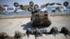 FILE - South Korean (blue headbands) and U.S. Marines take positions as amphibious assault vehicles of the South Korean Marine Corps fire smoke bombs during a U.S.-South Korea joint landing operation drill in Pohang, South Korea, March 12, 2016. 