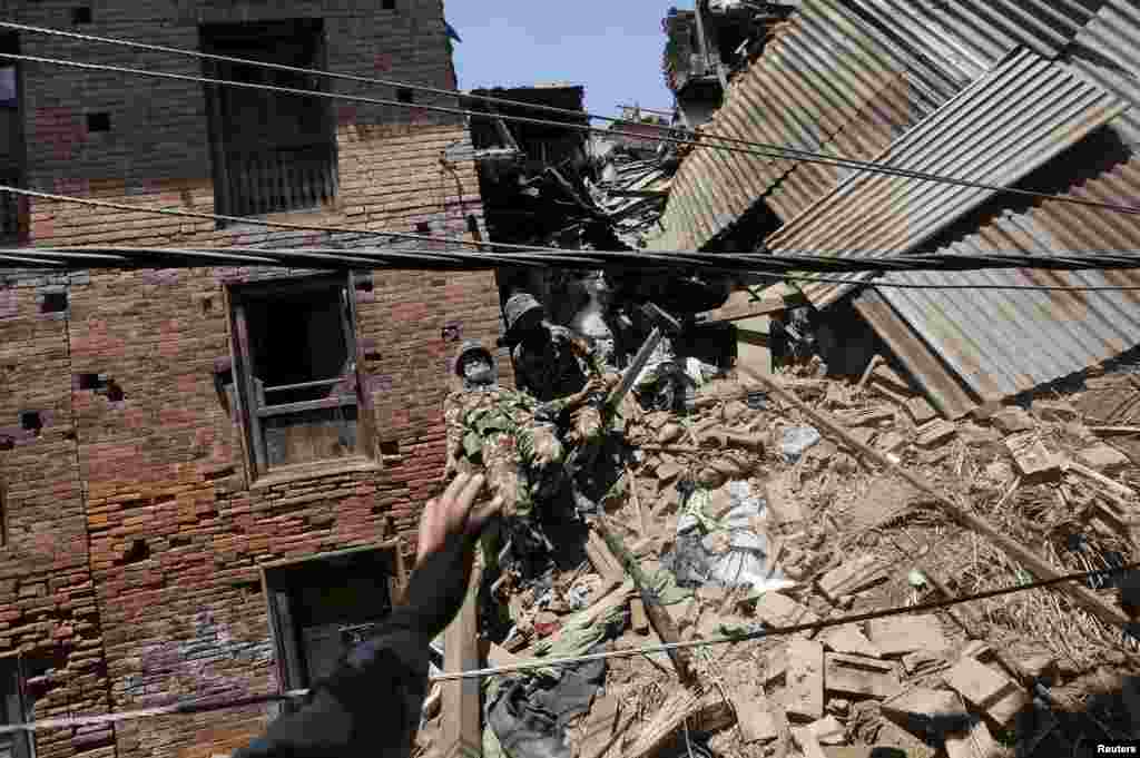 A Nepalese army soldier descends from a mound of rubble during the recovery of a body in the aftermath of Saturday's earthquake in Bhaktapur, Nepal.