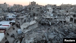 Palestinians walk among the rubble of buildings, In Khan Younis