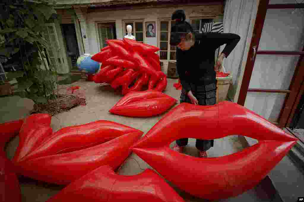 Artist and environmental activist Kong Ning prepares inflatable lip-shaped balloons with a theme "Kiss the earth" in support on Earth Day in Beijing, China.