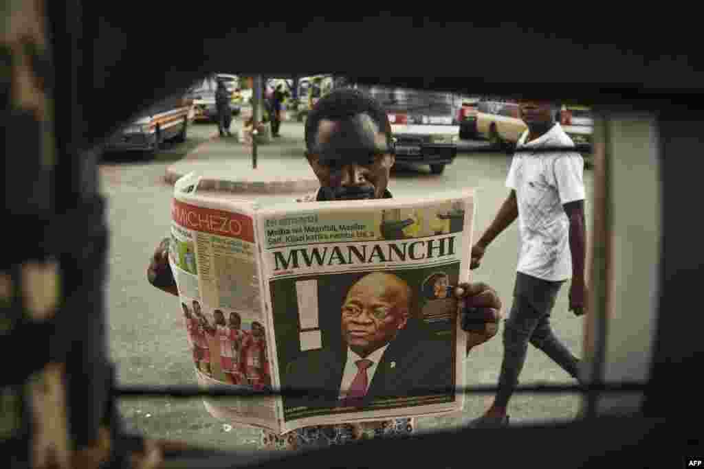 A man reads a newspaper with a headline announcing the death of Tanzania's President John Magufuli in Dar es Salaam.