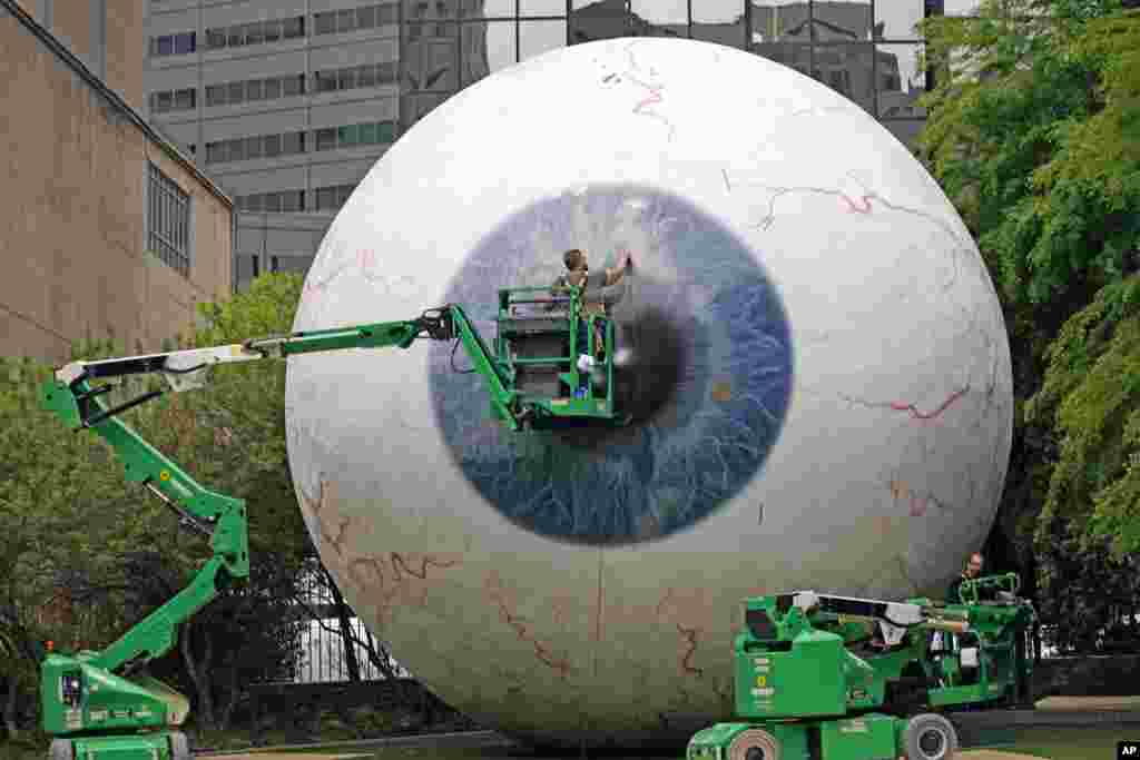 Workers restore the fiberglass sculpture called "The Eye" created by artist Tony Tasset in downtown Dallas, Texas. The he 30-foot giant eye was vandalized.