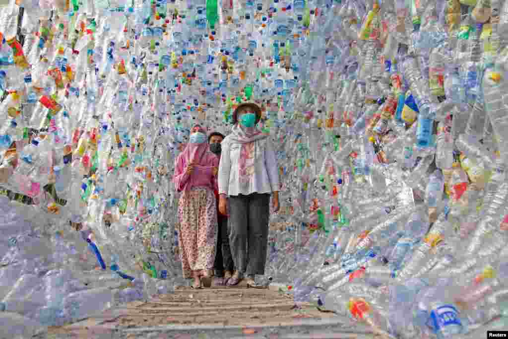 People walk through "Terowongan 4444" or 4444 tunnel, built from plastic bottles collected from several rivers around the city in three years, at the plastic museum constructed by Indonesia's environmental activist group Ecological Observation and Wetlands Conservation (ECOTON) in Gresik regency near Surabaya, East Java province, Indonesia.