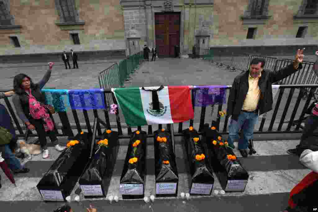 Para demonstran berdiri dekat enam peti mati yang mewakili mereka yang tewas dalam serangan polisi di negara bagian Guerrero, saat berdemonstrasi di luar Istana Nasional di Mexico City (1/11). (AP/Marco Ugarte)
