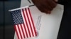 ARCHIVO - Maweya Babekir, de Iowa City, Iowa, sostiene una bandera antes de prestar juramento de lealtad durante una ceremonia de naturalización en Principal Park, el viernes 26 de junio de 2020, en Des Moines, Iowa.