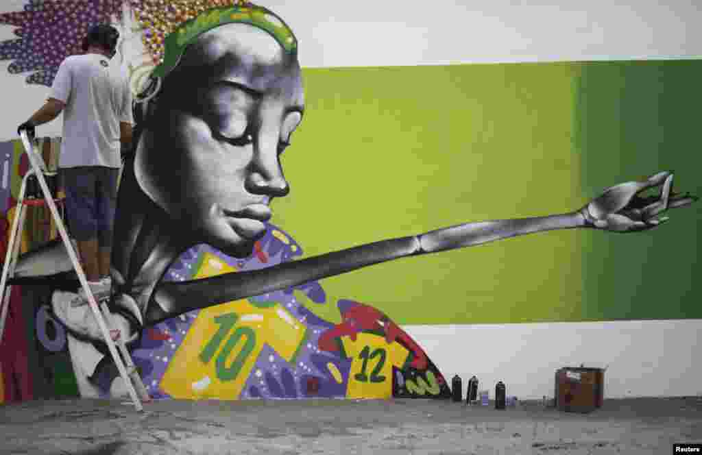 Seniman grafiti Barba bekerja pada mural dalam rangka perayaan kejuaraan sepak bola Piala Dunia 2014 di Rio de Janeiro, Brasil. Mural itu akan menjadi bagian dari sebuah kontes yang diselenggarakan oleh balai kota di kota itu. 