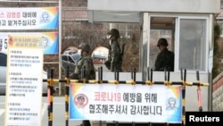 Tentara Korea Selatan mengenakan masker untuk mencegah penularan virus corona, saat bertugas di pos pemeriksaan pangkalan militer di Daegu, Korea Selatan, 26 Februari 2020. (Yonhap via REUTERS)