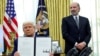 Президент США Дональд Трамп держит в руках указ о повышении тарифов. Рядом с ним в Овальном кабинете Белого дома министр торговли США Говард Латник. 13 февраля 2025 года. REUTERS.