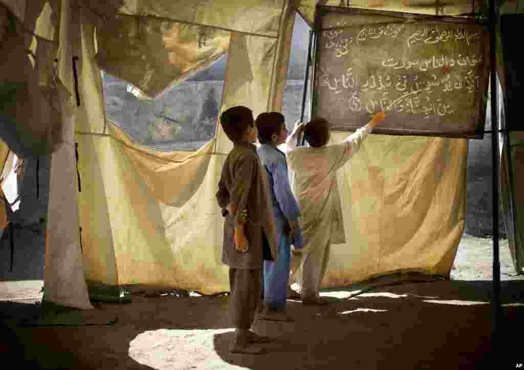 Anak laki-laki Afghanistan belajar di sekolah darurat di desa Budyali, Nengarhar Provinsi, Afghanistan.