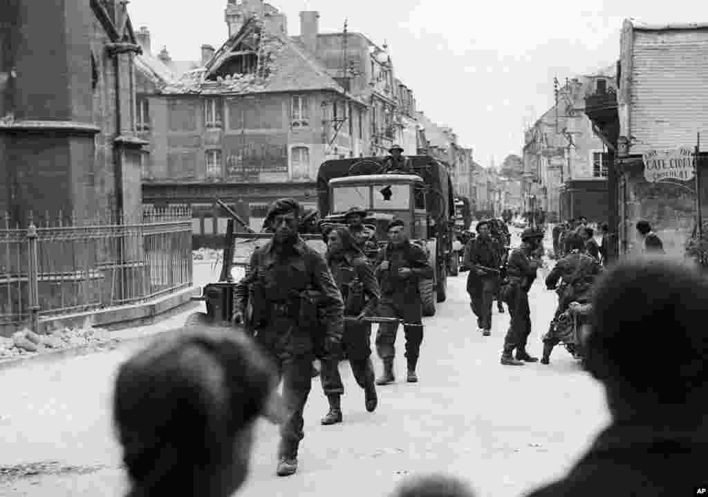 British commandos pass through the streets of a town near Caen, France, June 6, 1944.