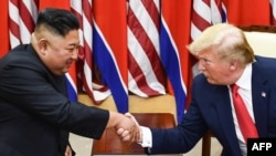 FILE - North Korea's leader Kim Jong Un (L) and U.S. President Donald Trump shake hands during a meeting on the south side of the Military Demarcation Line that divides North and South Korea, in the Demilitarized zone (DMZ) of Panmunjom, June 30, 2019. 