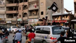 Anggota kelompok negara Isalam dan Levant (ISIL) membawa bendera mereka berpawai keliling wilayah Raqqa, Irak (29/6).