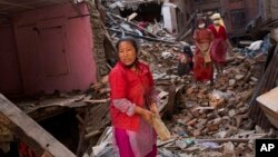 Nepalese women search for belongings from their house that was destroyed in the earthquake in Bhaktapur, Nepal. Nepal was repaying $220 million a year to international lenders before the quake. (AP Photo/Bernat Amangue)