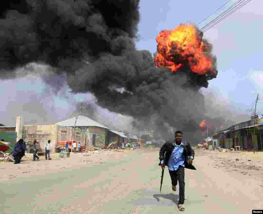 A Somali policeman runs from the scene of an accidental explosion at a fuel storage facility within the former United States residential housing in capital Mogadishu.