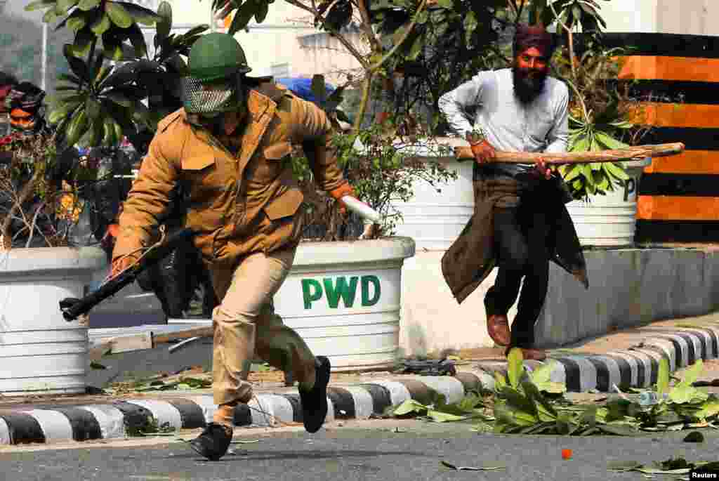 Seorang petani berlari di belakang seorang petugas polisi selama aksi protes menentang undang-undang pertanian yang baru disahkan oleh pemerintah, di New Delhi, India, 26 Januari 2021. (Foto: REUTERS / Adnan Abidi) 