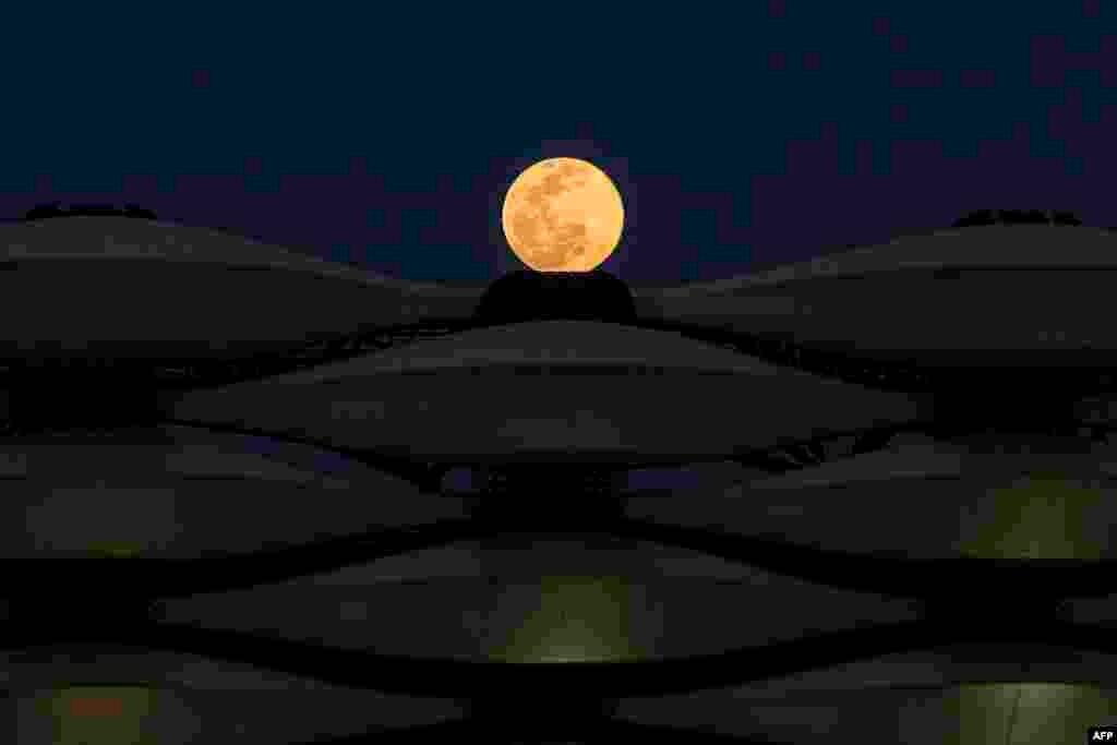 A view of the rising full "Worm Moon" above Basra International Stadium in the southern Iraqi city, March 28, 2021.