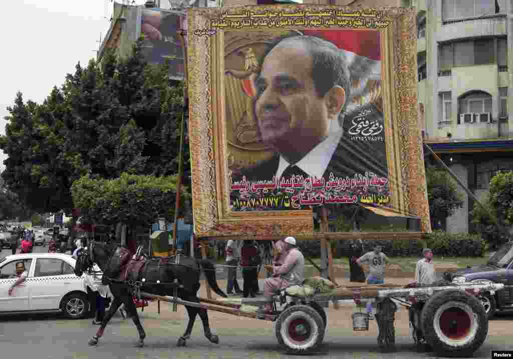 Seorang pria dengan gerobak yang ditarik kuda melewati spanduk besar mantan komandan angkatan darat Abdel-Fattah el-Sissi, di pusat kota Kairo (6/5). (Reuters/Mohamed Abd El Ghany)