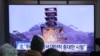 People watch a TV screen showing a file image of a ground test of North Korea's rocket engine during a news program at the Seoul Railway Station in Seoul, South Korea, Monday, Dec. 9, 2019.