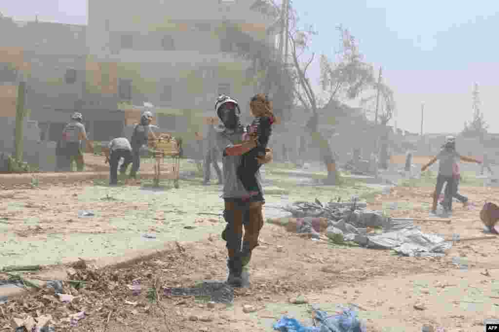 Seorang petugas penyelamatan Suriah menggendong seorang anak di distrik Maadi, Aleppo (27/8). (AFP/Ameer Alhalbi)
