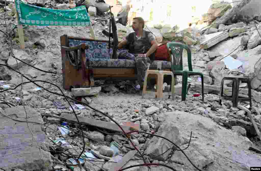 A Free Syrian Army fighter sits on a sofa along a street in Aleppo's Salaheddine neighborhood, July 31, 2013
