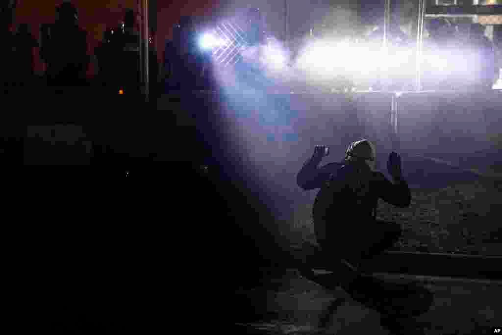 Police shine lights on demonstrator with raised hands during a protest over Sunday's fatal shooting of Daunte Wright during a traffic stop, outside the Brooklyn Center Police Department in Brooklyn Center, Minnesota.