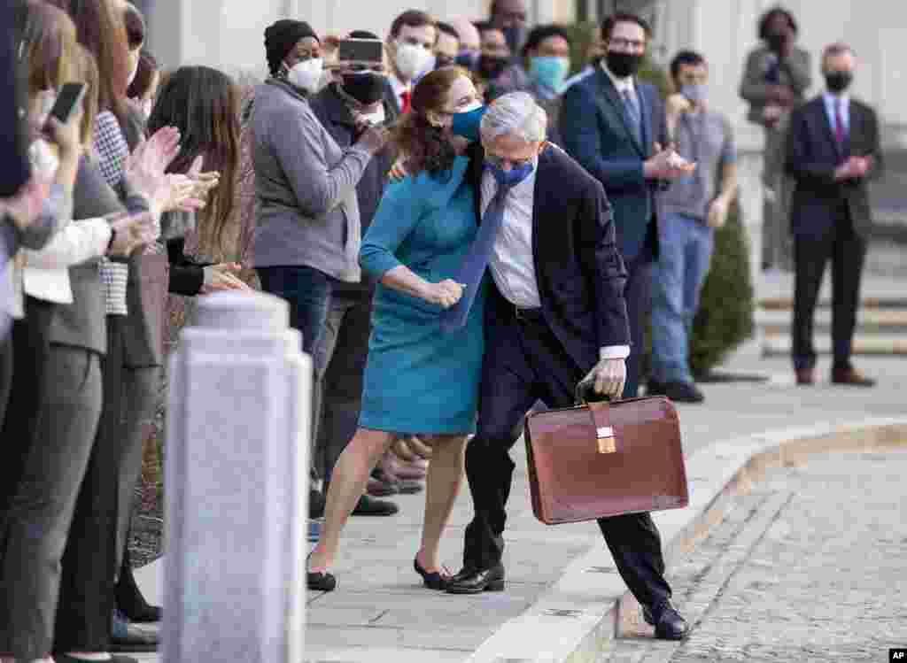 President Joe Biden's pick for attorney general Merrick Garland hugs his wife Lynn as he arrives for his first day at the Department of Justice in Washington, D.C.