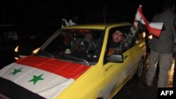 Un conductor sirio ondea una bandera nacional mientras la gente celebra en las calles de Alepo, Siria, después de que el ejército anunciara que había recuperado el total control de la ciudad.