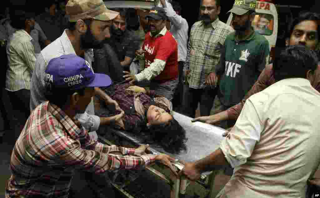 People rush a woman to an emergency ward of a hospital after a bombing outside a mosque in Karachi, Pakistan, November 21, 2012.